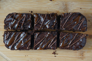Flatlay view of  moist dark chocolate brownies over wooden table.