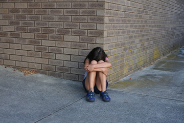 Sad young girl crying outside female toilet building