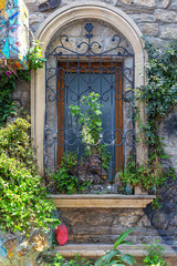 Fototapeta na wymiar Arched window in an old stone house with wrought iron bars