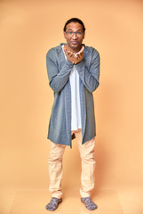 Vertical portrait of a cheerful young man wearing glasses African-American with a short haircut in ordinary clothes on a pink background in full length. Standing right in front of the camera