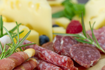 Beautiful sliced food arrangement close-up photo. Italian style antipasto plate, cheese, ham, salami, rosmarin, prosciutto
