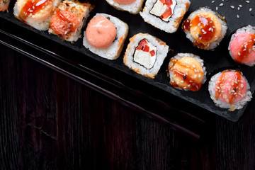 Sushi rolls assortment served on slate plate on black table