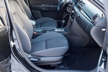 Comfortable front seats inside the car: the driver and passenger, tied with genuine black leather, modern interior design, the steering wheel covered with black wood and a luxurious center console.