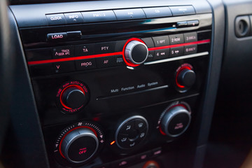 Air conditioning on the dashboard climate control car inside the cabin close-up with red illumination of buttons and levers with a display that measures the temperature and direction of air.