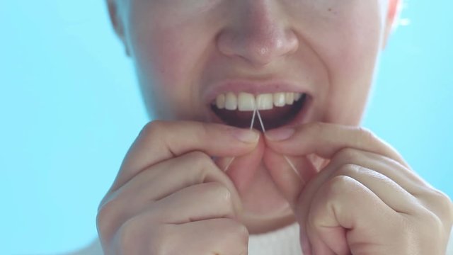 Girl brushes her teeth with floss closeup front view.