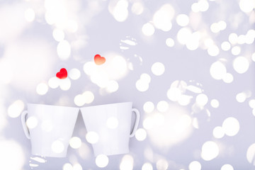 White china mug with glitter heart confetti. Valentine day concept. Trendy minimalistic flat lay design background. Horizontal with festive bokeh lights