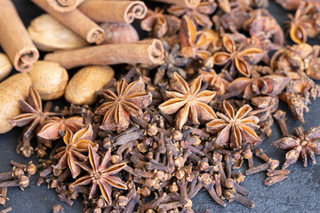 Different spices cinnamon, cloves, star anise on wooden box and nutmeg. Traditional Christmas smell and winter spices background.