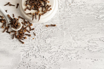 Natural clove spice on ehite concrete background with copy space.