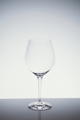 Red wine glass on the light background.. Fine cristal glassware concept. Vertical, cold tone in light cold toning