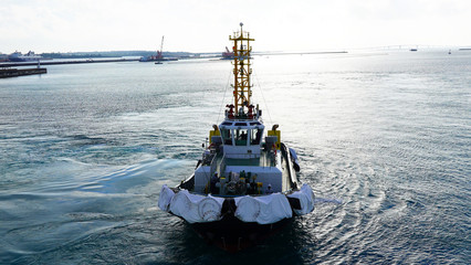 A bright, powerful, new, industrial tug helps the ship maneuver in port. A tugboat helps moor a...