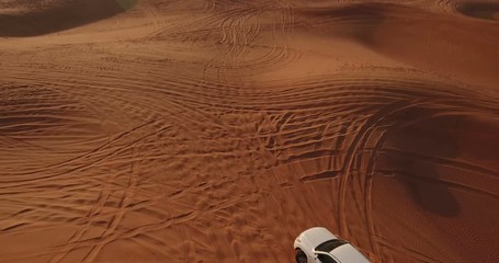 Aerial view of 4x4 off road land vehicle taking tourists on desert dune bashing safari in Dubai, UAE