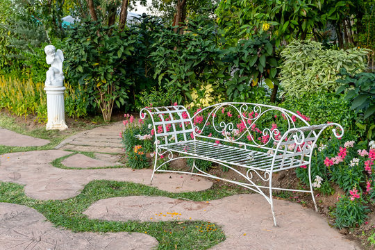 White metal bench in beautiful flower garden, Garden bench.