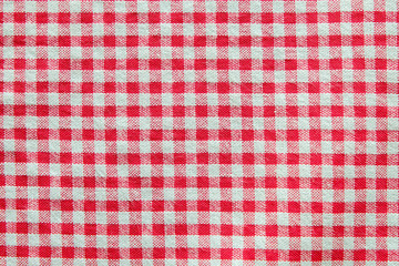 Top view of red and white gingham tablecloth table cover in the restaurant. Napkin on food table. Fabric detail surface. Kitchen and eatery background wallpaper concept with copy space for text.