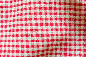 Top view of red and white gingham tablecloth table cover in the restaurant. Napkin on food table. Fabric detail surface. Kitchen and eatery background wallpaper concept with copy space for text.