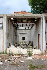 Destroyed tall garage at abandoned industrial complex with missing front wall and demolished roof...