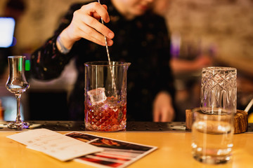 Bartender prepairing a cocktail at the bar. Stirring a drink in the mixing glass with a bar spoon....
