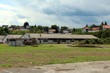 Elongated dilapidated military hangars with broken windows and destroyed walls surrounded with...