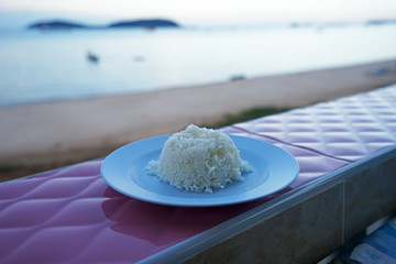 Close up plate of steamed white rice with sea view