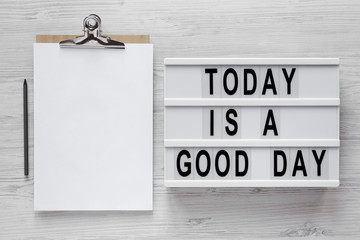 'Today is a good day' words on a modern board, clipboard with blank sheet of paper on a white...