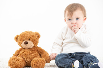 Studio photo Baby with his hand in the mouth with a teddy bear