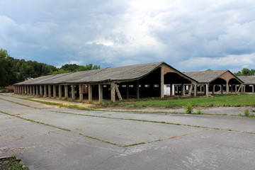 Row of densely built wide large hangar buildings with missing destroyed red brick support walls and...
