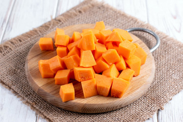 Cubes of pumpkin on cutting board on wooden table