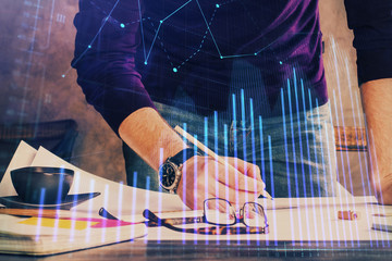 Double exposure of man writing on paper with forex graph.