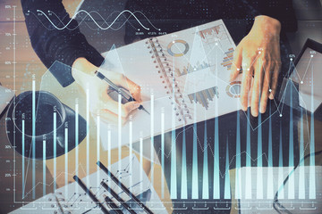 Multi exposure of hands making notes with forex chart huds. Stock market concept.