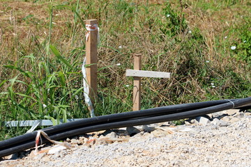 Bunch of dark plastic water pipes left waiting for installation at local construction site next to...