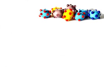 Beautiful colorful cheerful background made of handmade lampwork beads with dots. Beads are situated top right, isolated on white background. Suitable for text insert.