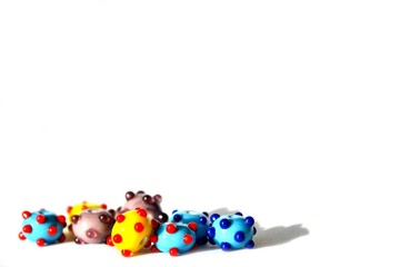 Beautiful colorful cheerful background made of handmade lampwork beads with dots. Beads are situated bottom left, isolated on white background. Suitable for text insert.