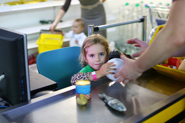 Four year old caucasian toddler girl playing to be a cashier at the supermarket