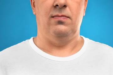 Mature man with double chin on blue background, closeup