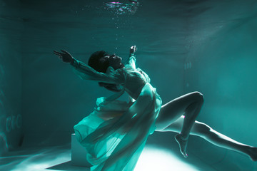Beautiful girl swims underwater in a yellow dress. 2020 New Year trend Aqua Mente and fatom blue and lush lava. Underwater girl mermaid. Model suitable for advertising