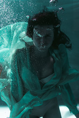 Beautiful girl swims underwater in a yellow dress. 2020 New Year trend Aqua Mente and fatom blue and lush lava. Underwater girl mermaid. Model suitable for advertising