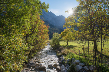 Fototapeta na wymiar karwendel valley with rissbach brook and trees in autumnal colors. sunny landscape in october