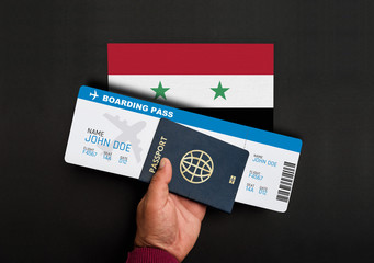 Hand holds passport and boarding pass with flag of Syria