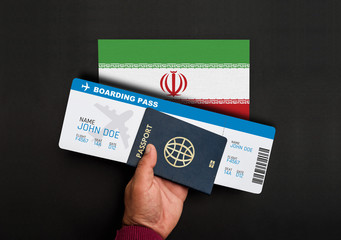 Hand holds passport and boarding pass with flag of Iran