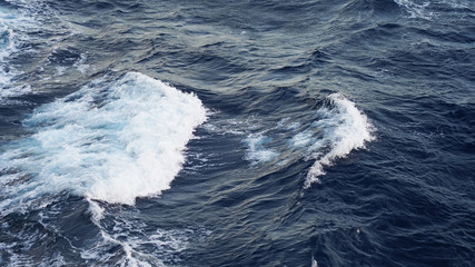 Sea ​​waves in the storm. dark blue water of the Pacific Ocean, white foam on the waves. pure salt water texture