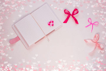 Valentines day flatlay. Blank diary, pink heartshaped beads, hearts and purple ribbon bow on white background. Notebook mockup,cute bokeh lights. Space for wishes text, sign. Lovers day,8 march banner