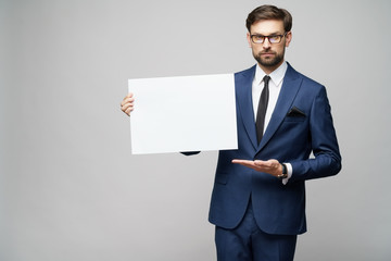 Young businessman holding blank signs over grey background