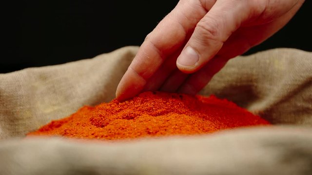 Adult male hand touching a red pepper powder in a sac