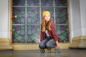 Lifestyle outdoor portrait of young smiling teenage girl  with a yellow skateboard