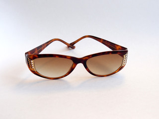 Brown-rimmed sunglasses, women's accessory. Summer season, sea, beach.
