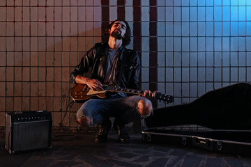 A street musician playing on guitar in the underpass. Vagrant lifestyle. Playing in the underpass...