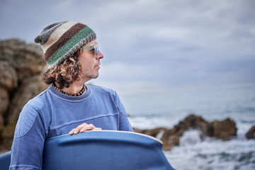 portrait of a middle-aged man with a surfboard in the sea looking at the horizon