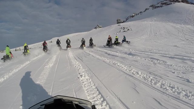 POV: Ryder is chasing a group of snowmobilers on a snow sports motorcycles. group riding on elite snowmobiles in a mountain valley. the concept of winter motorcycle tourism. First-person view