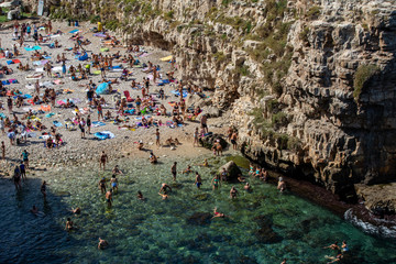  People relax and swimming on lovely beach Lama Monachile in Polignano a Mare, Adriatic Sea, Apulia, Bari province, Italy,