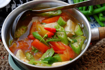 Vietnamese vegan soup in pot from vegetables are okra, tofu, tomato