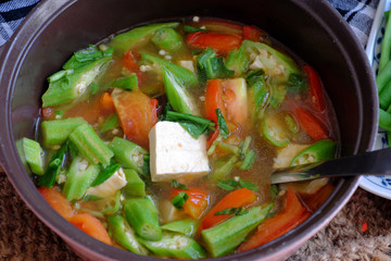 Vietnamese vegan soup in pot from vegetables are okra, tofu, tomato